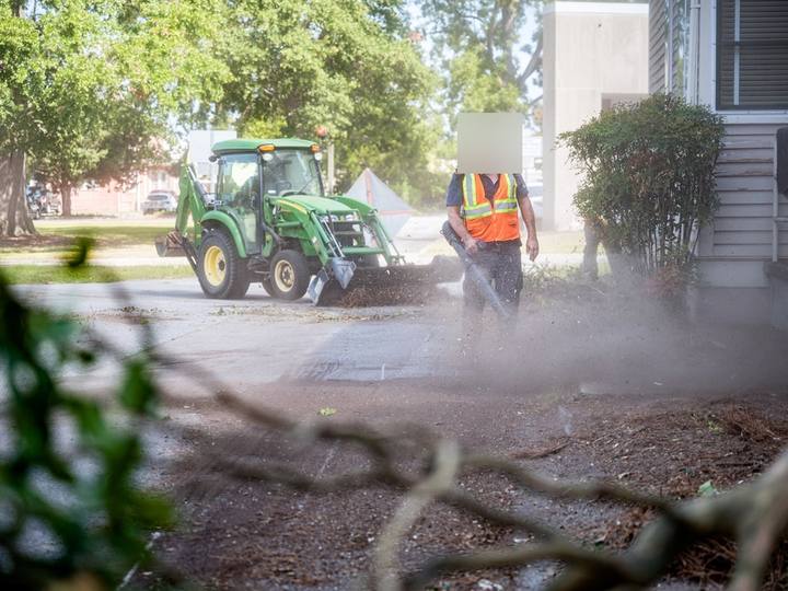 Example photo: a worker with a blower and a tractor on a driveway