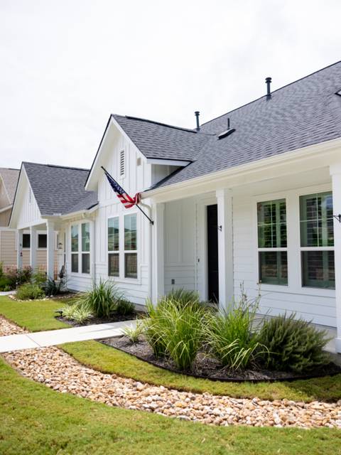 A white house with a fresh bed and a green lawn