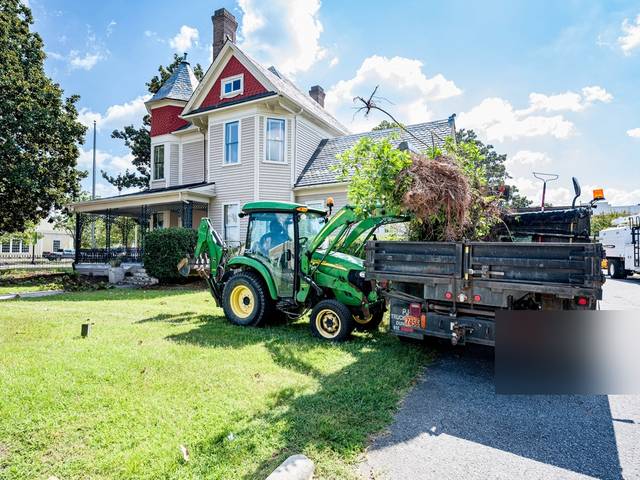 A tractor with a dump trailer by a house
